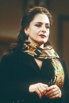 a woman wearing a scarf and looking off to the side with her hand on her hip