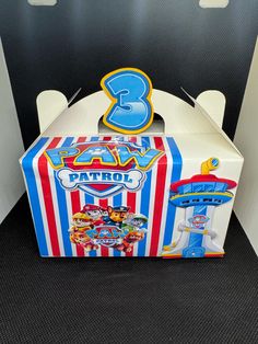 a birthday cake box with the number 3 on it and an image of a carnival tent