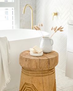 a bathroom with a white bath tub and wooden stool