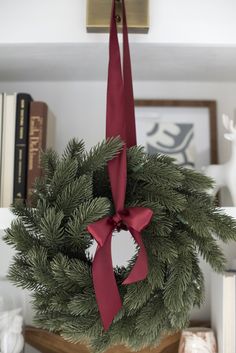 a christmas wreath hanging from the ceiling with a red bow on it's front