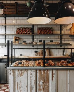 a bakery with lots of baked goods on the counter and hanging lights over it's windows