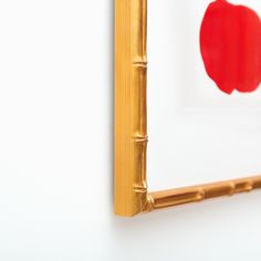 a red apple painted on the side of a white wall next to a gold frame