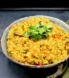 a bowl filled with rice and vegetables on top of a table