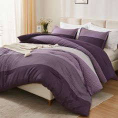 a bed with purple comforter and pillows in a room