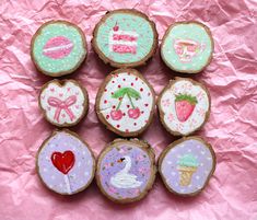 six decorated cookies sitting on top of a pink paper covered table next to each other