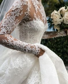 a woman wearing a wedding dress and veil with flowers in her hair is holding a bouquet