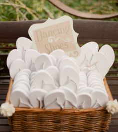 a basket filled with white shoes sitting on top of a wooden bench next to a sign