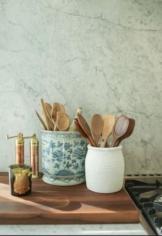 kitchen utensils and wooden spoons in a ceramic container on a counter top