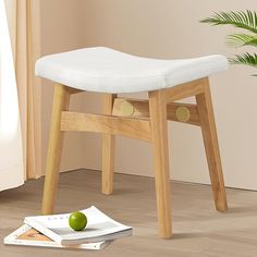 a wooden stool with a white cushion on top of it next to a green apple