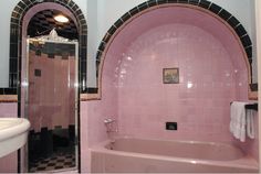 a pink bath tub sitting next to a white sink in a bathroom under two mirrors