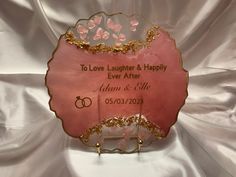 a pink and gold wedding sign with two rings on the front that says to love laughter & happily ever after