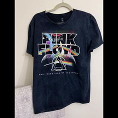 a black shirt with pink floyd on it hanging from a hanger next to a white wall