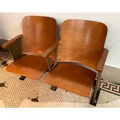 two brown chairs sitting next to each other on a tiled floor in front of a wall