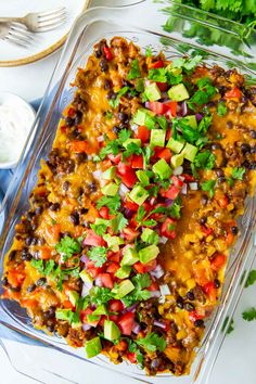 a glass casserole dish filled with mexican food and garnished with cilantro