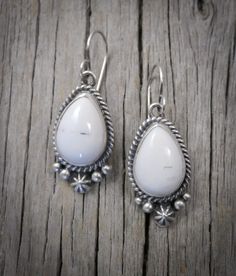 100% handcrafted from Sterling Silver and White Buffalo; Navajo Native American silversmiths are recognized among the finest in the world. This work of art features striking, rare, White Buffalo stones. This stunning semi precious gemstone is smooth white in color and is marked with a touch of black matrix. This is that go to accessory that you can wear often due to the neutral nature of the stones and will quickly become your signature! Measures: 1 1/2" x 9/16" (with ear wires) 10 grams Stamped Elegant Untreated White Jewelry, Artisan White Sterling Silver Jewelry, Artisan White Jewelry Stamped 925, White Artisan Jewelry Nickel Free, White Sterling Silver Jewelry With Gemstone, Southwestern Teardrop Gemstone Jewelry, Southwestern Style Teardrop Gemstone Jewelry, White Artisan Drop Earrings, Unique White Sterling Silver Jewelry