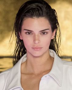 a close up of a person wearing a white shirt and hair in a ponytail with long bangs