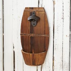 a wooden wall mounted bottle opener on the side of a white painted wood planked wall