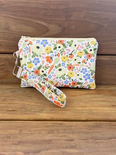 This pretty floral Easter themed grab and go wristlet makes a great gift as a makeup bag, cell phone wristlet or wallet.  This handheld clutch and trendy purse is great to grab on the go!  This is the perfect size bag when looking to take only your phone and a few extras, like cash, credit cards and some lip gloss!  Each bag has a wrist strap that is made from matching fabric.  Each wrist strap is approximately 6.25" long including the hardware.  The fabric of the wristlet is 5.25" not including the hardware.  Features: Size: approximately 7.5" wide x 5" tall Fabric: 100% cotton + interfacing for added durability YKK zipper *Please note that there are no pockets on the interior of the bag* Makes a great girl gift or holiday gift!  Spot clean only with damp cloth. Spring Gift Wristlet With Wrist Strap, Spring Rectangular Phone Bag With Cell Phone Pocket, Handheld Wristlet With Zipper Closure As Gift, Spring Rectangular Wristlet With Wrist Strap, Spring Rectangular Wristlet, Pouch Wristlet With Zipper Closure For Gift, Pouch Wristlet As Gift, Wristlet Pouch With Wrist Strap As Gift, Pouch Wristlet With Wrist Strap As Gift