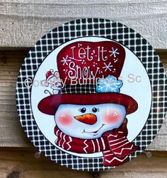 a snowman with a red hat and scarf on it's head is hanging from the side of a wooden wall