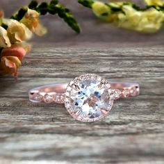 a close up of a ring on a wooden surface with flowers in the back ground