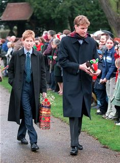 a man and boy walking down a path with people watching them from behind him on the other side