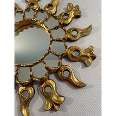 a mirror that is sitting on top of a white surface with gold trimmings