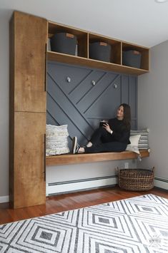 a woman sitting on a bench in front of a book shelf with baskets and bins