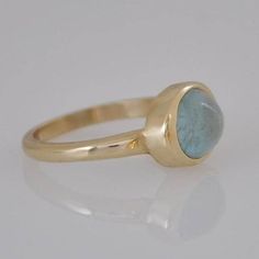 "Beautiful 14k gold ring with blue aquamarine stone for a woman. Elegant gold gift for the woman you love! This 14k gold ring is a perfect, unique, modern ring for every woman. This Aquamarine gold ring is relatively heavy yet maintains a gentle look. The bezel of the ring is intentionally wider than in typical engagement ring bezel, so you can see more gold around the cabochon aquamarine stone. Dimensions: * 14k solid gold * Oval Aquamarine : 8 * 10 m\"m I use natural gemstones in my jewelry wh Modern Oval Blue Topaz Ring, Modern Blue Topaz Oval Ring, Aquamarine Oval Birthstone Ring, Modern Oval Aquamarine Rings, Aquamarine Birthstone Ring, Oval, Modern Aquamarine Oval Rings, Gift Sapphire Ring With Oval Tension Setting, Oval Sapphire Ring With Tension Setting As Gift, Aquamarine Topaz Ring With Bezel Setting