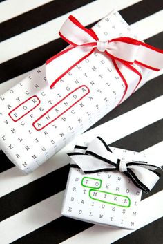 two wrapped presents sitting on top of a black and white striped tablecloth with red ribbon