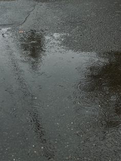 an umbrella sitting on the side of a road in the rain with puddles all over it