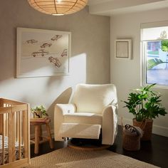 a baby's room with a rocking chair, crib and potted plants