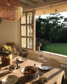 a cat sitting on the window sill looking out at an outside area with table and chairs