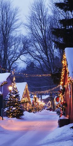 A snow-covered village with cottages adorned with twinkling Christmas lights, creating a cozy holiday atmosphere perfect for a winter-themed wallpaper. Snowy Wallpaper, Cozy Village, Village Street, Winter Iphone