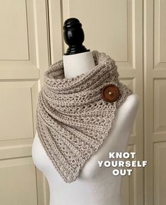 a white mannequin wearing a gray knitted cowl with a wooden button