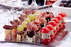 an assortment of appetizers are displayed on a silver platter with grapes and meat