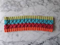 a multicolored knitted headband laying on top of a marble countertop