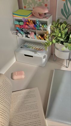 an open book sitting on top of a desk next to a plant