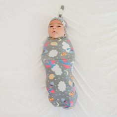 a baby wrapped in a sleeping bag with clouds and stars on it's head