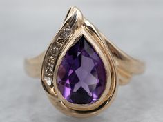 Here we've taken a vintage gold and champagne diamond mounting and set it with our own stone! This is a wonderful gem, an amethyst with precise faceting and with rich, deep color. The teardrop, pear-shaped cut reflects a great deal of light from within the stone! This luxurious piece will transition well from office to evening!Metal: 14K Yellow GoldGem: Amethyst 1.70 CaratsGem Measurements: 9.4 x 6.7 mm, PearAccents: 5 Diamonds totaling .08 Carats, SI in Clarity, Champagne in Color Ring Size: 6.75Marks: “14K” Stamped on the inside band Formal Pear-shaped Amethyst Ring With Prong Setting, Formal Teardrop Amethyst Ring In Fine Jewelry Style, Elegant Pear-shaped Amethyst Ring For Formal Occasions, Elegant Formal Pear-shaped Amethyst Ring, Elegant Teardrop Amethyst Gemstone Ring, Teardrop Amethyst Ring For Formal Occasions, Elegant Teardrop Amethyst Ring For Formal Occasions, Teardrop Amethyst Ring For Anniversary, Purple Amethyst Teardrop Ring