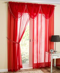 red sheer curtains in front of a window with a mirror and lamp on the floor