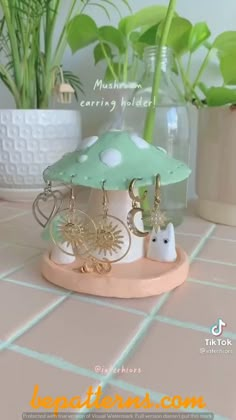 a green and white mushroom with earrings in it on a table next to potted plants