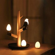 a lamp that is sitting on top of a table next to two candles and a bird figurine