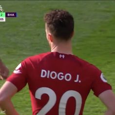 a soccer player is standing on the field with his back to the camera and has his hands in his pockets