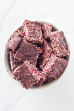 a white bowl filled with chocolate and raspberry fudges on top of a marble counter