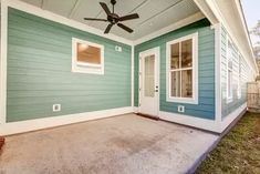 a blue and white house with a ceiling fan on the front porch, next to a door