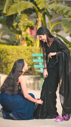 two women sitting on the ground talking to each other