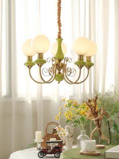 a green chandelier hanging over a dining room table with flowers in vases