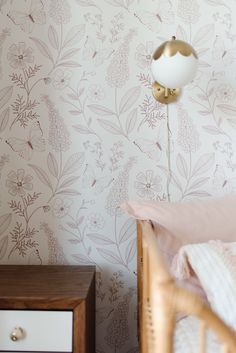 a bedroom with floral wallpaper and a white lamp on the side table next to it