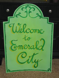 a green sign that says welcome to emerald city on the side of a black dresser