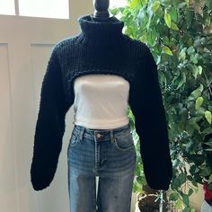 a woman's sweater and jeans on display in front of a potted plant